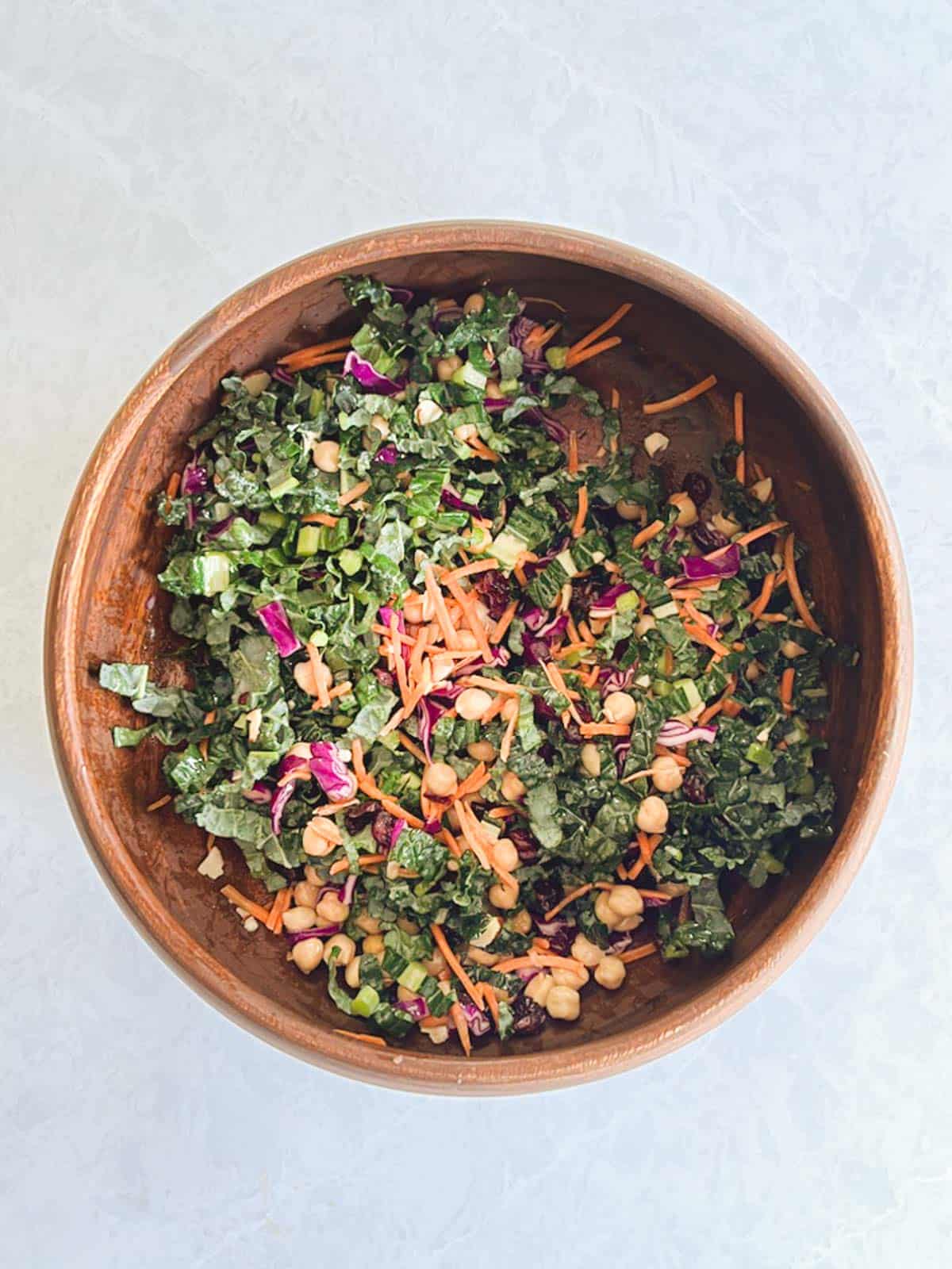 overhead of large wooden bowl containing autumn quinoa salad ingredients tossed with dressing