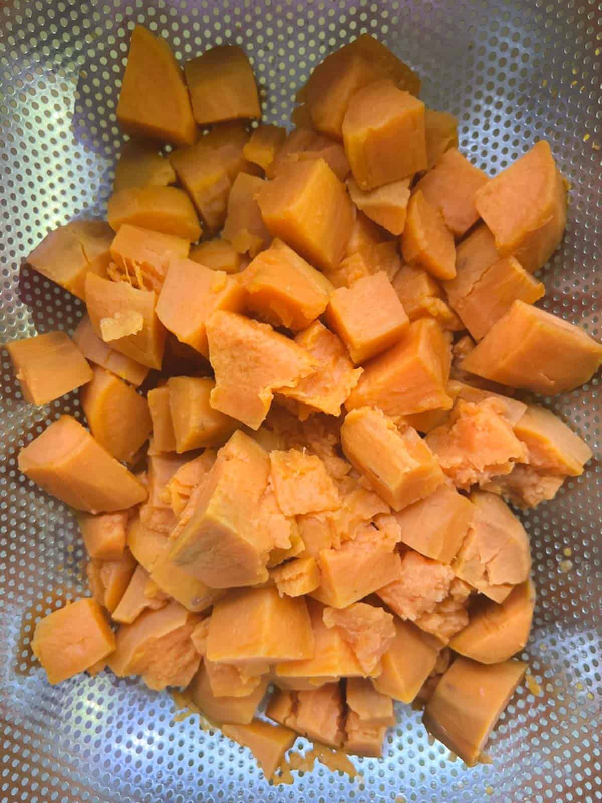 cooked potato cubes draining in a colander