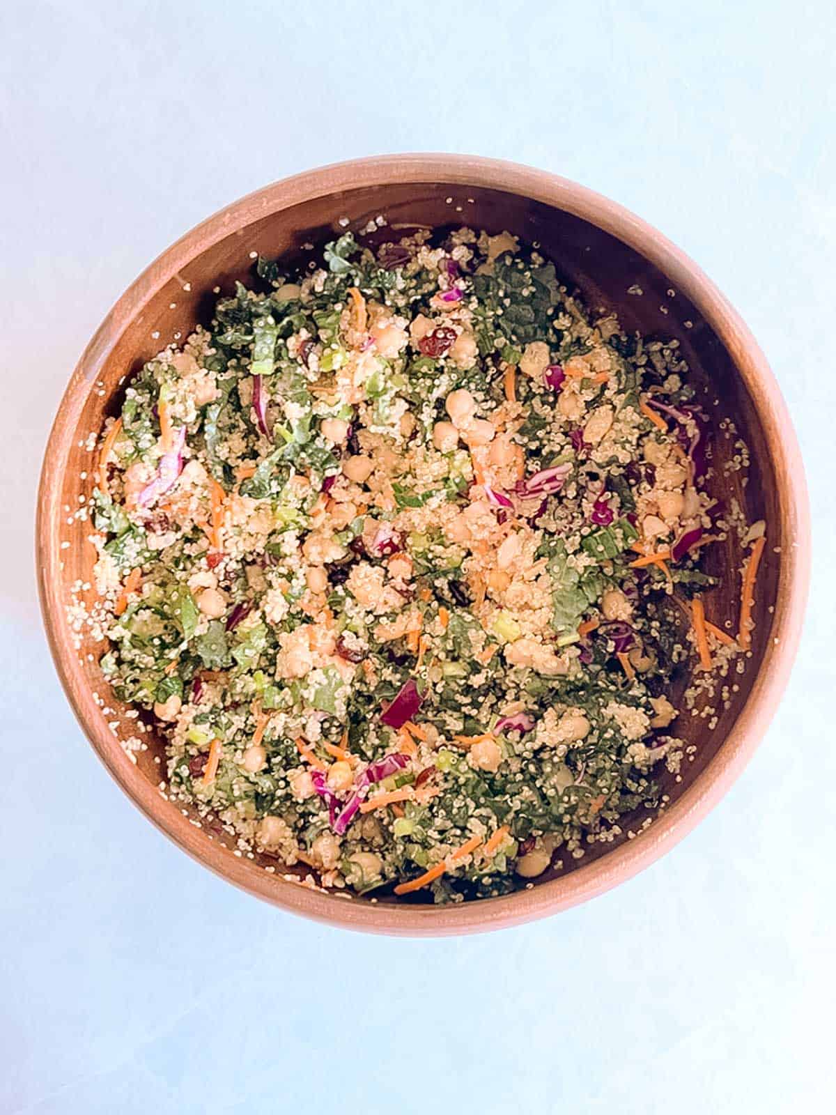 overhead of large wooden bowl of autumn quinoa salad with quinoa added