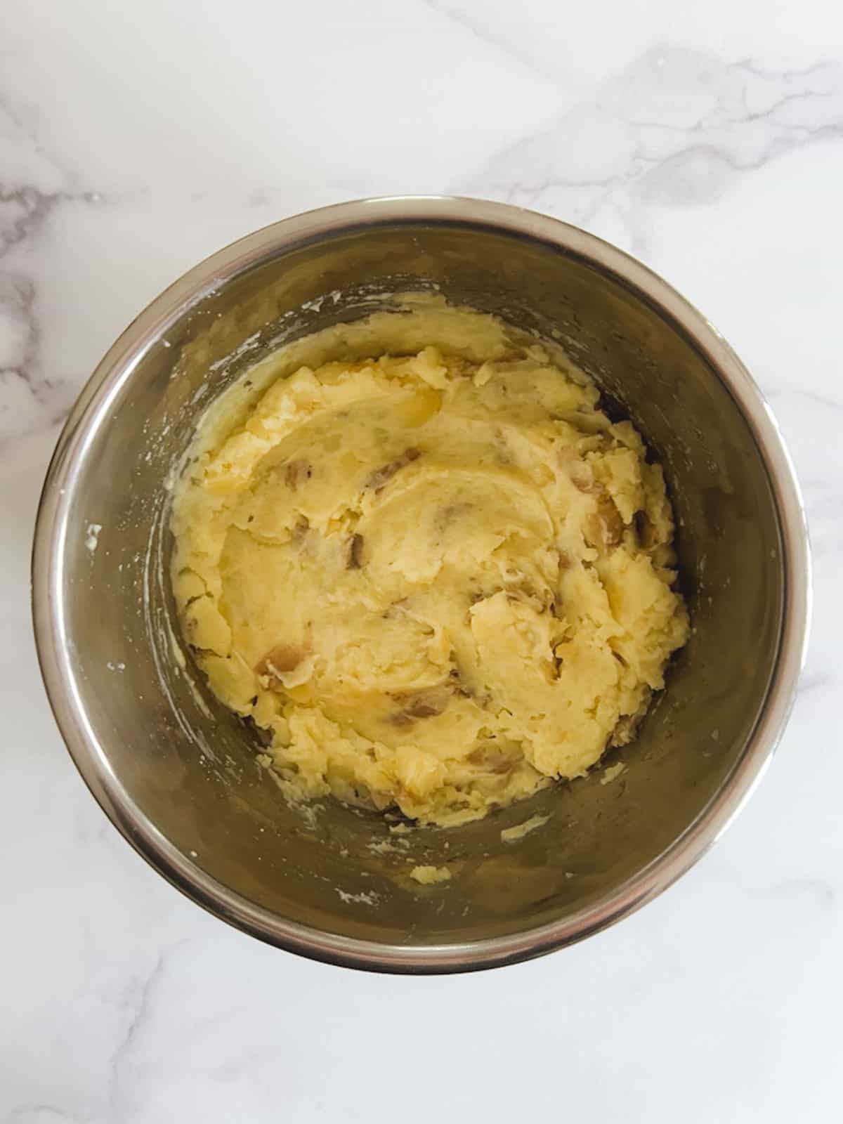 overhead view of mashed potatoes in inner pot with plant milk added