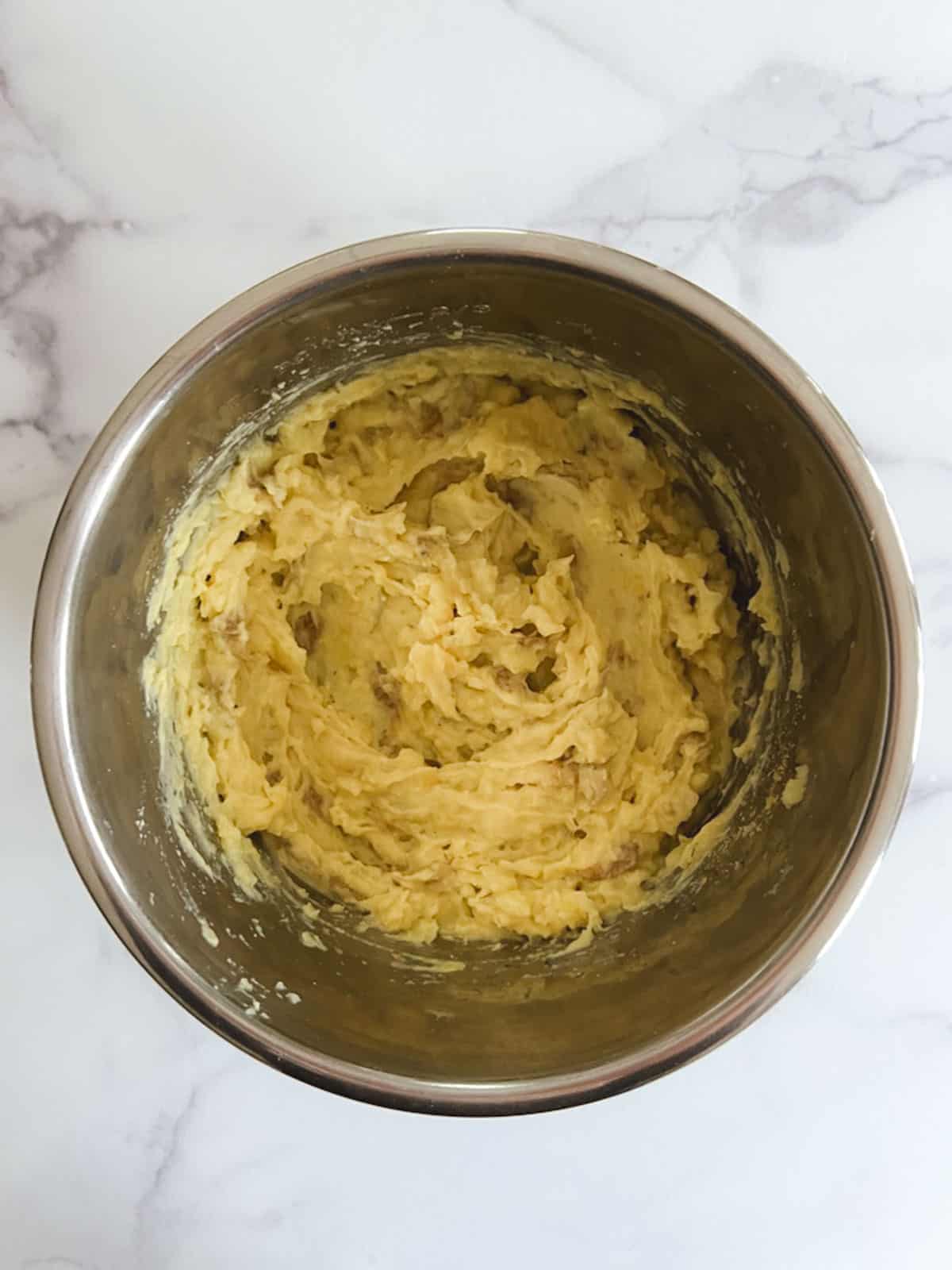 overhead view of mashed potatoes in inner pot with cheesy rosemary seasoning added