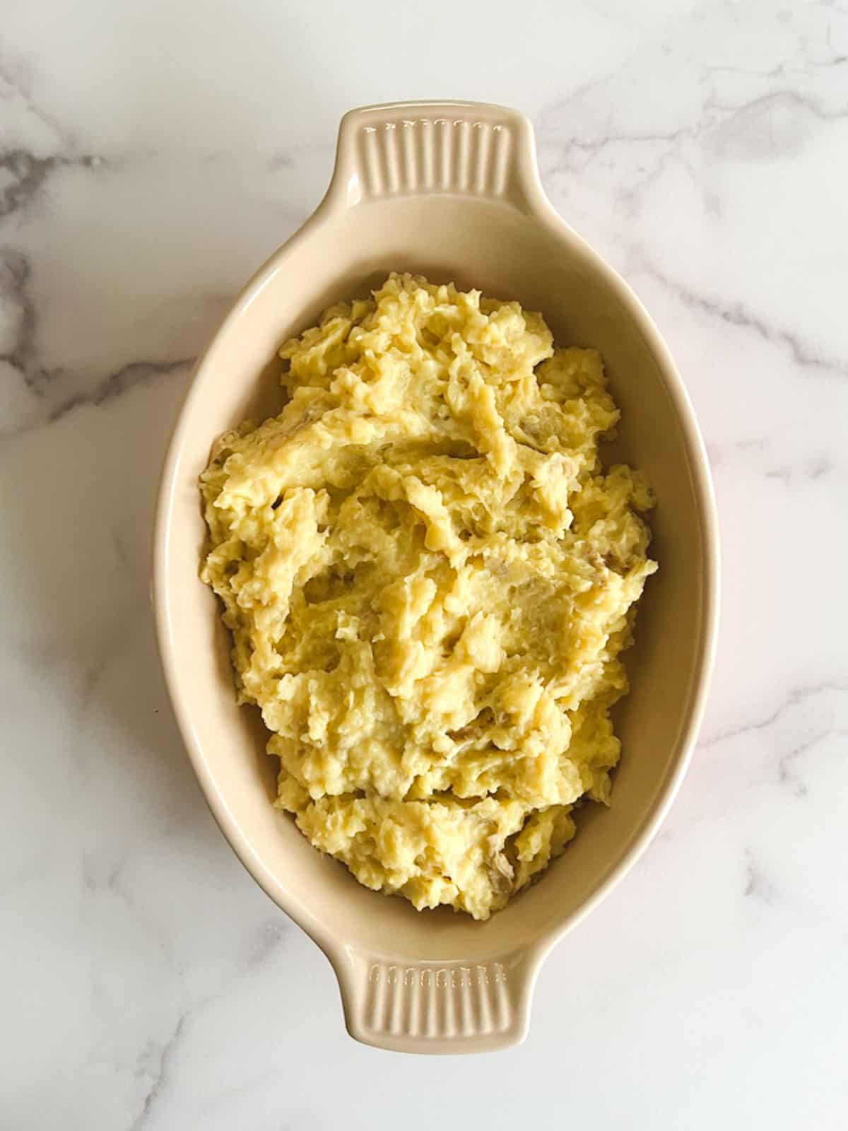 overhead view of oblong serving dish containing vegan instant pot mashed potatoes on a marble background