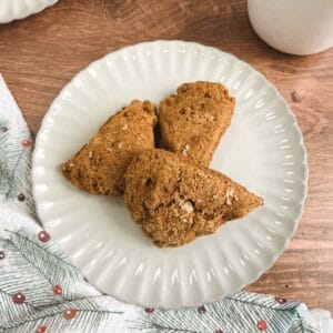 overhead view of a cream-colored plate holding 3 ginger pear scones next to a festive towel