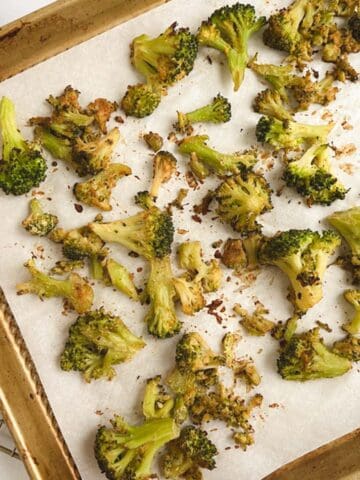 gold sheet pan lined with parchment paper containing oil-free roasted broccoli