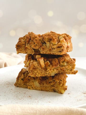 three squares of apple coffee cake stacked on a white plate