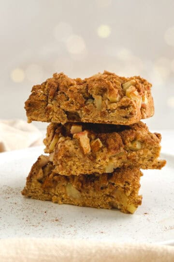 three squares of apple coffee cake stacked on a white plate