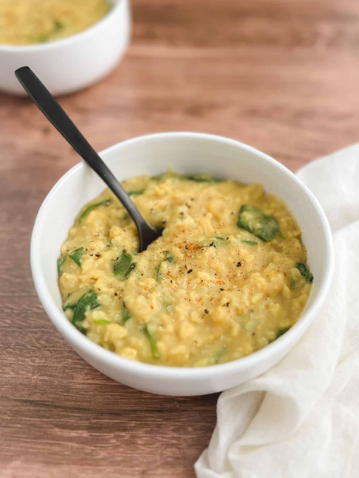 bowl of Instant Pot kitchari with a spoon in it on a wooden table