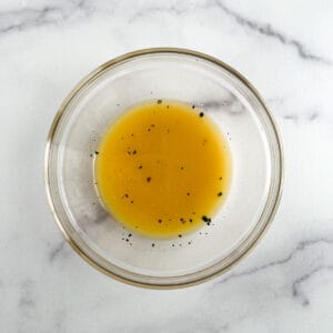 glass bowl of orange vinaigrette on a marble background