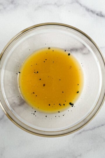 glass bowl of orange vinaigrette on a marble background