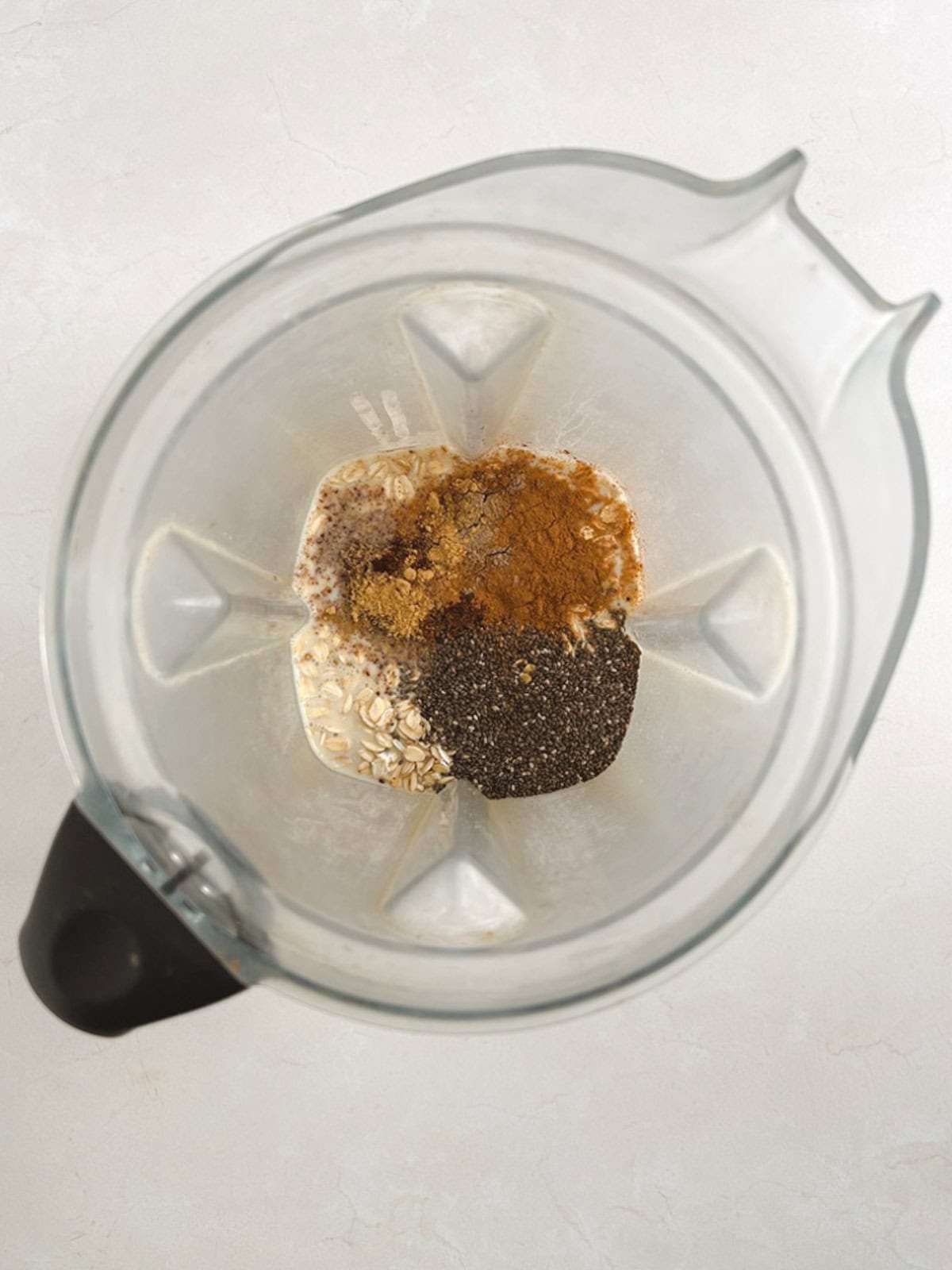 overhead view of blender containing unmixed ingredients for chai overnight oats