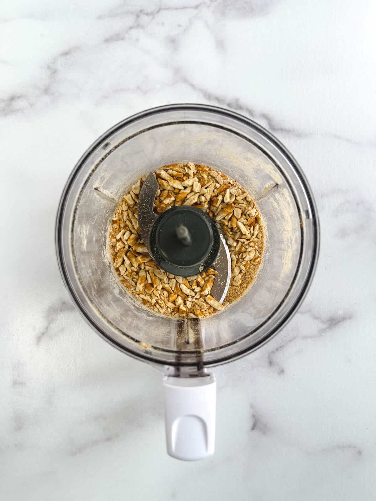 overhead view of small food processor containing crushed pretzel sticks