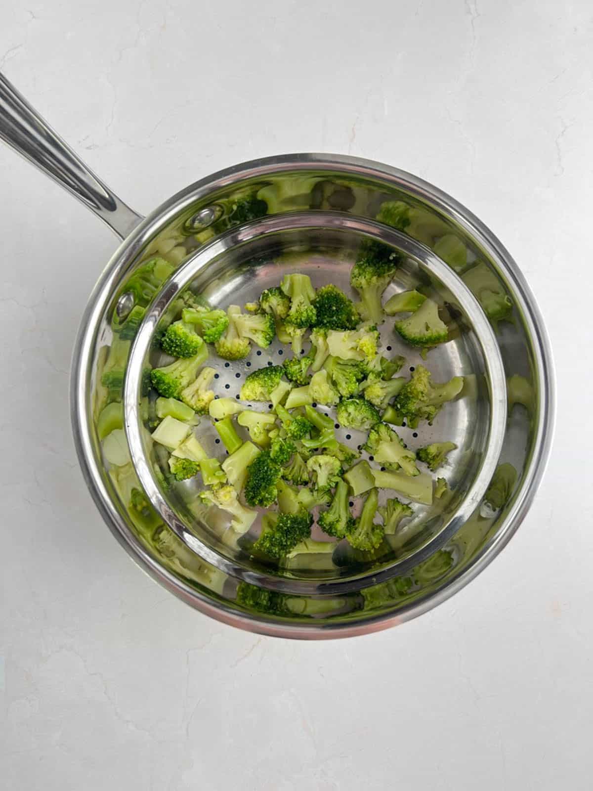 overhead view of steamer insert containing cooked broccoli florets