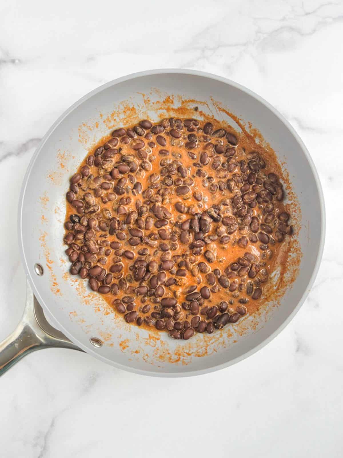 overhead view of skillet containing spicy black beans with sauce