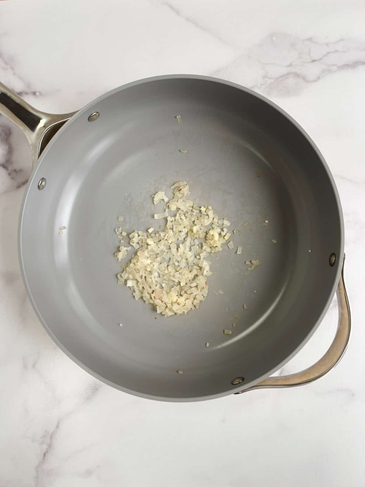 overhead view of sauté pan containing cooked shallots 