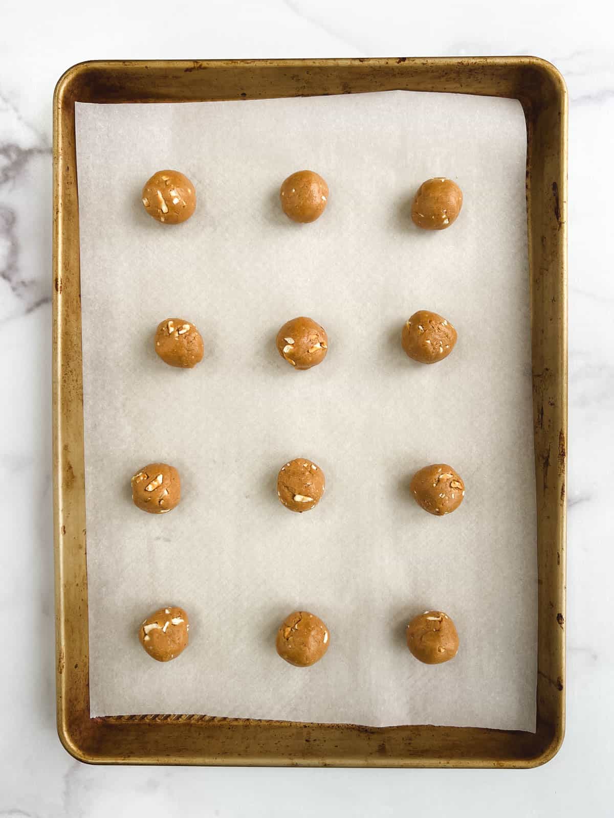 overhead view of prepared baking sheet with 12 balls of dough