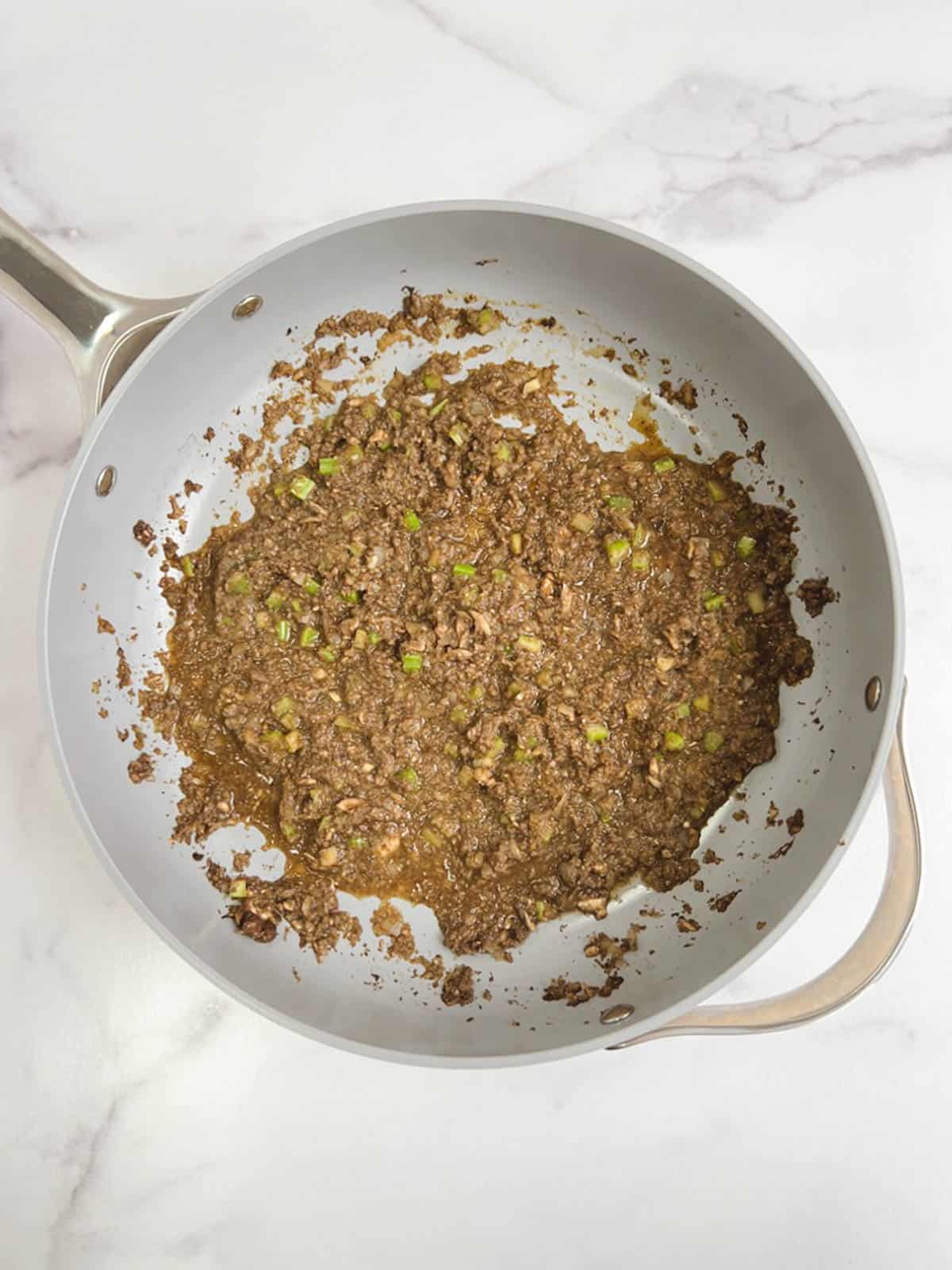 overhead view of sauté pan containing cooked shallots, mushrooms, celery, tamari, and miso