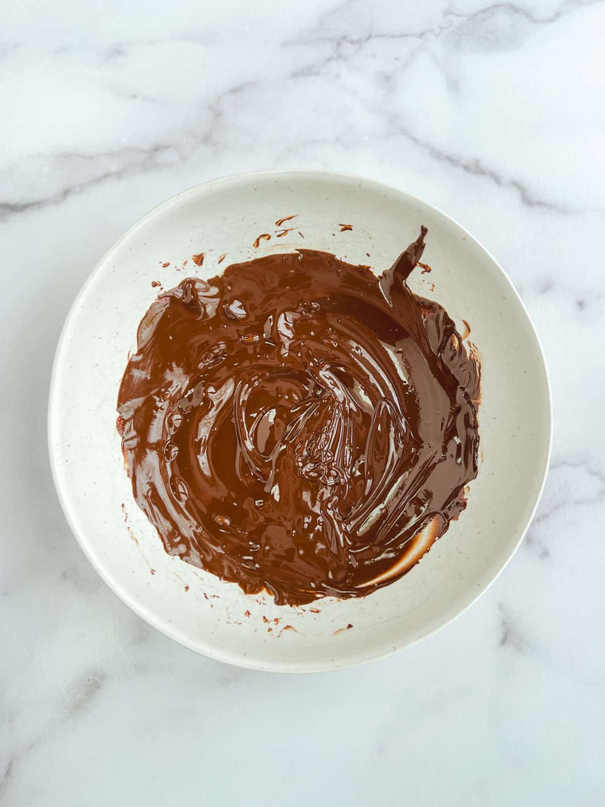 overhead view of white bowl containing melted chocolate 