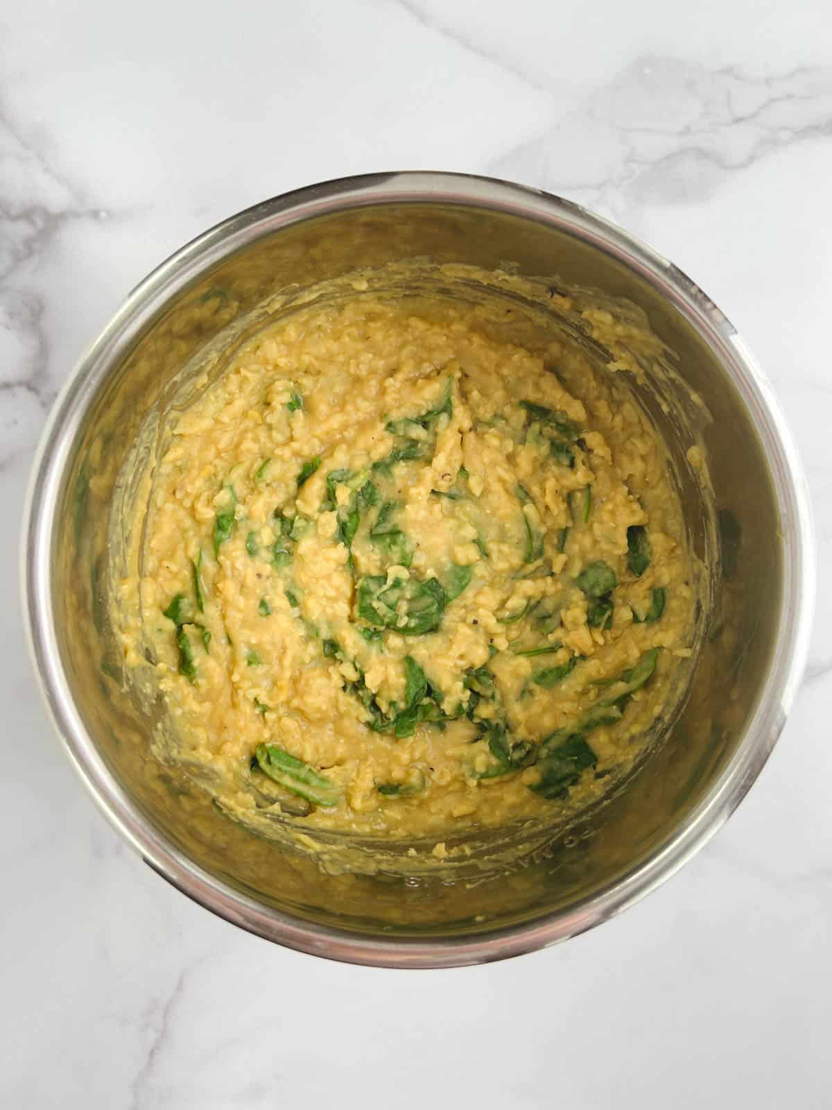 overhead view of Instant Pot inner pot containing cooked Instant Pot kitchari with spinach and lemon juice added