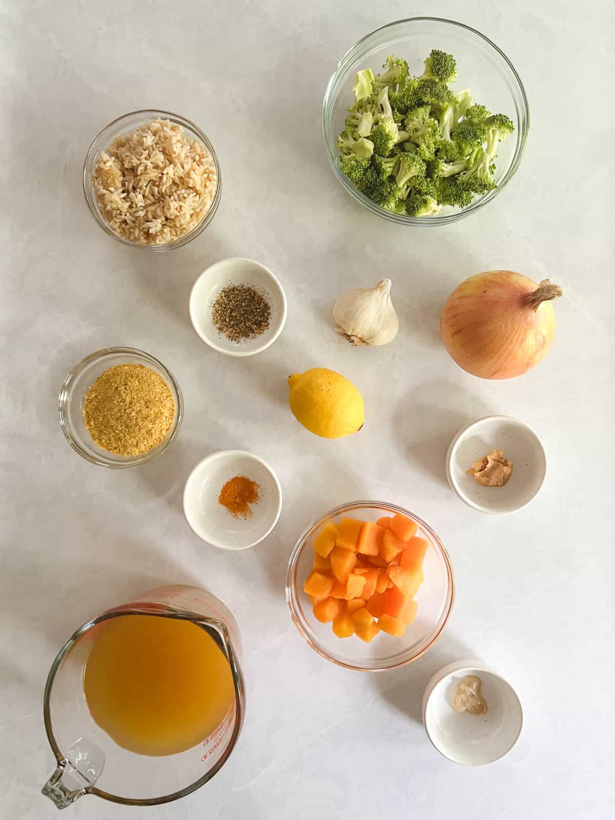 overhead view of bowls containing ingredients for vegan broccoli cheddar soup