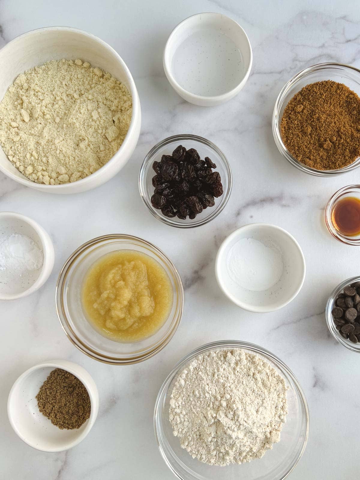 overhead view of bowls of ingredients for chocolate cherry scones on a white marble background