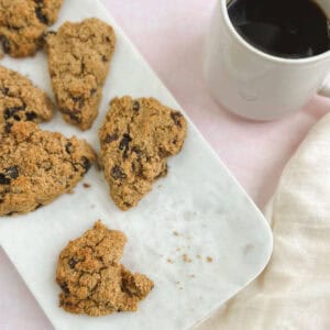 chocolate cherry scones on a marble serving tray next to a cup of coffee