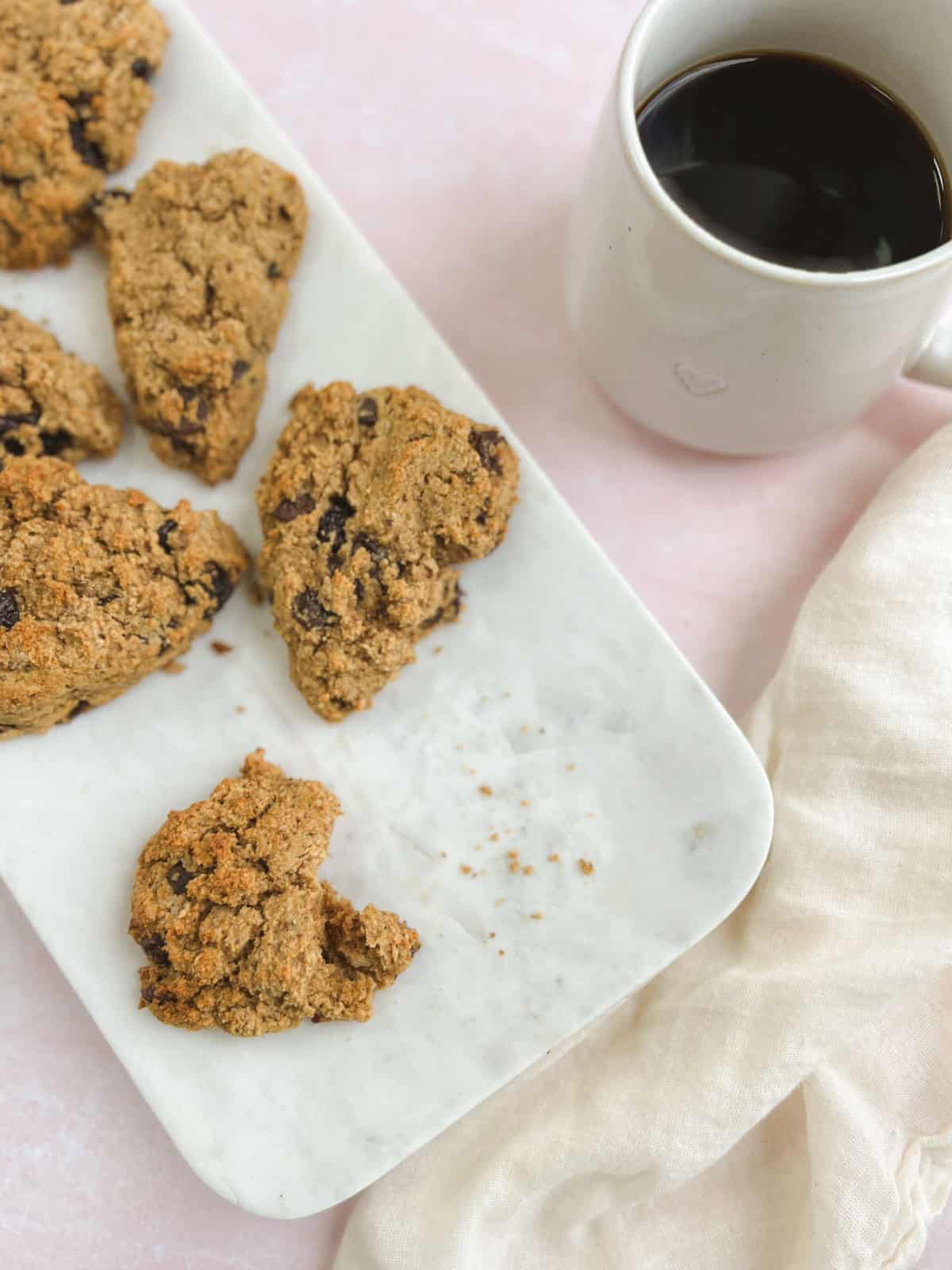 rectangular marble tray of chocolate cherry scones next to a cup of coffee