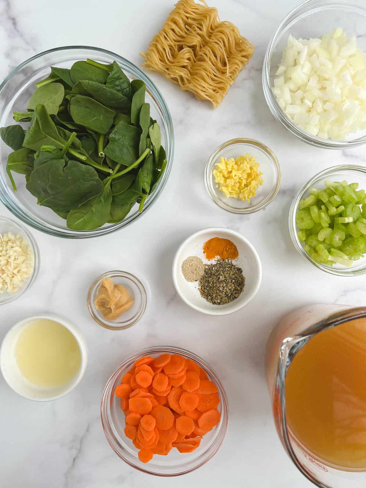 overhead view of glass bowls containing ingredients for immunity soup on a marble background