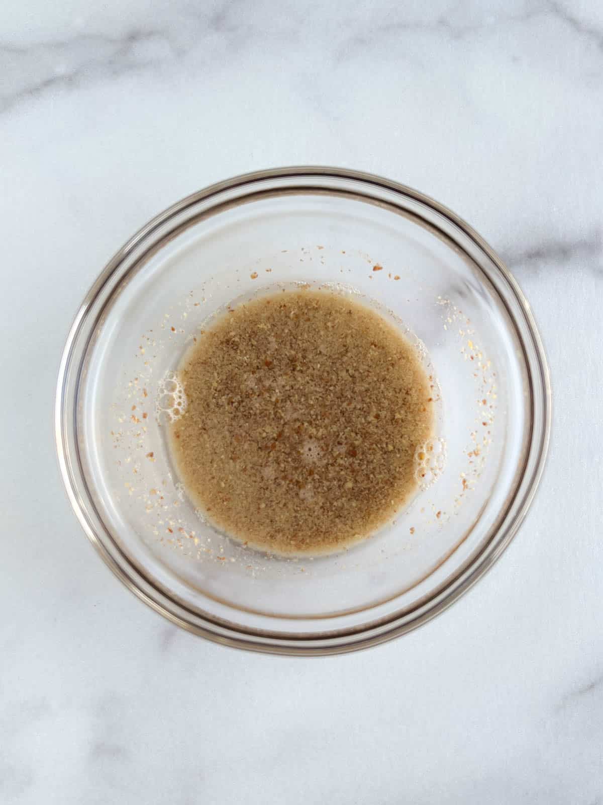 ingredients for flax egg mixed in a glass bowl on a marble background