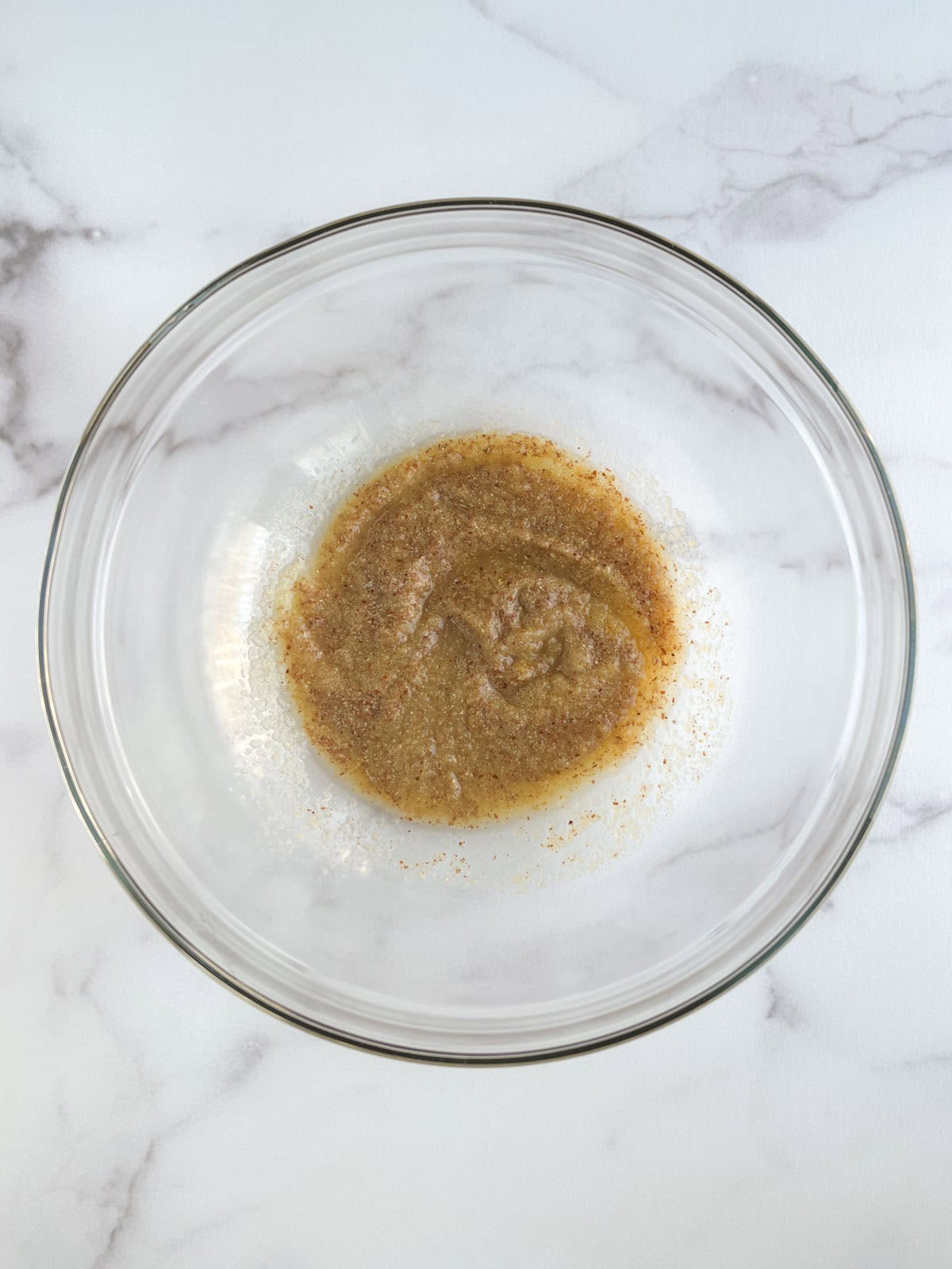 wet ingredients mixed in a glass bowl on a white marble background