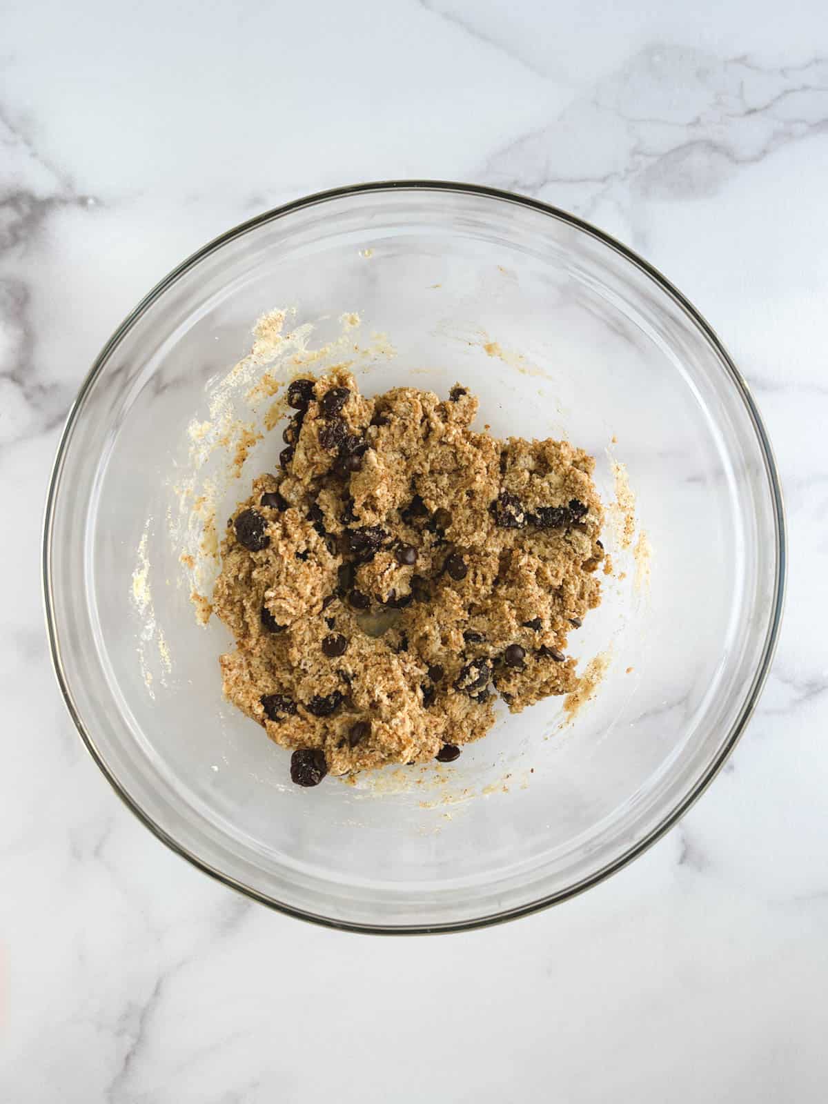 glass bowl containing wet and dry ingredients with cherries and chocolate chips added