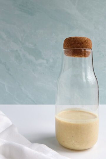 glass bottle of vegan caesar dressing next to a white napkin