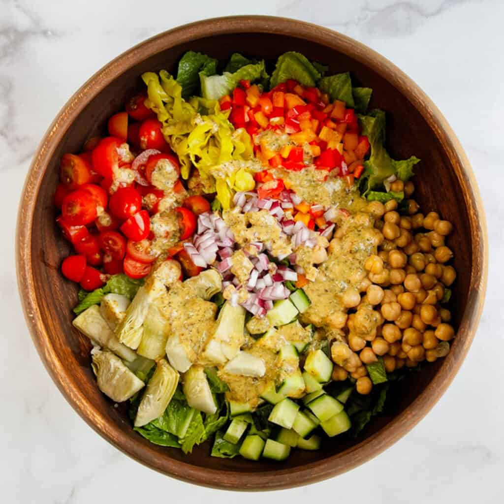 wooden bowl containing salad topped with italian dressing