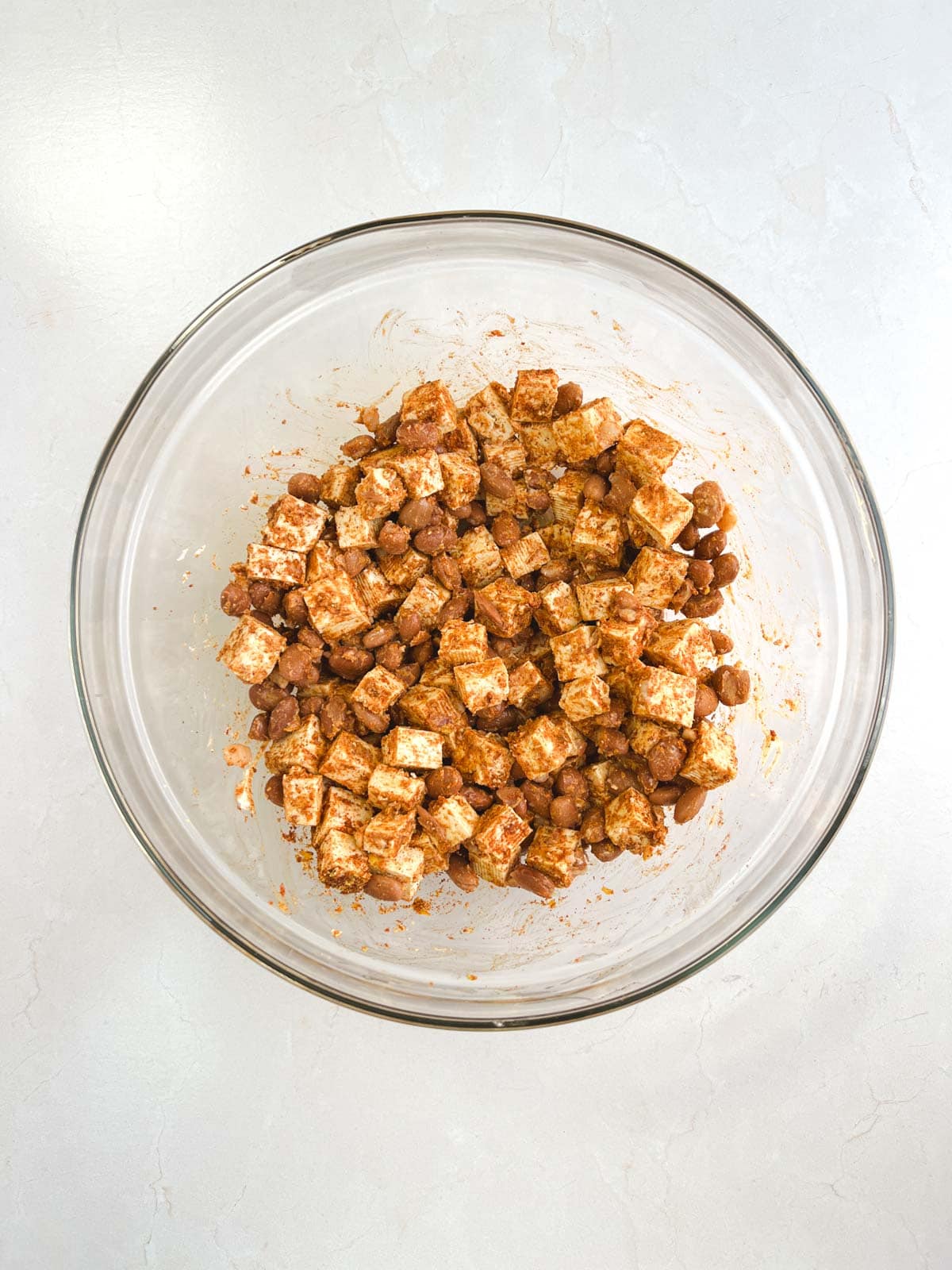 glass bowl containing mixture of tofu, beans, and seasoning