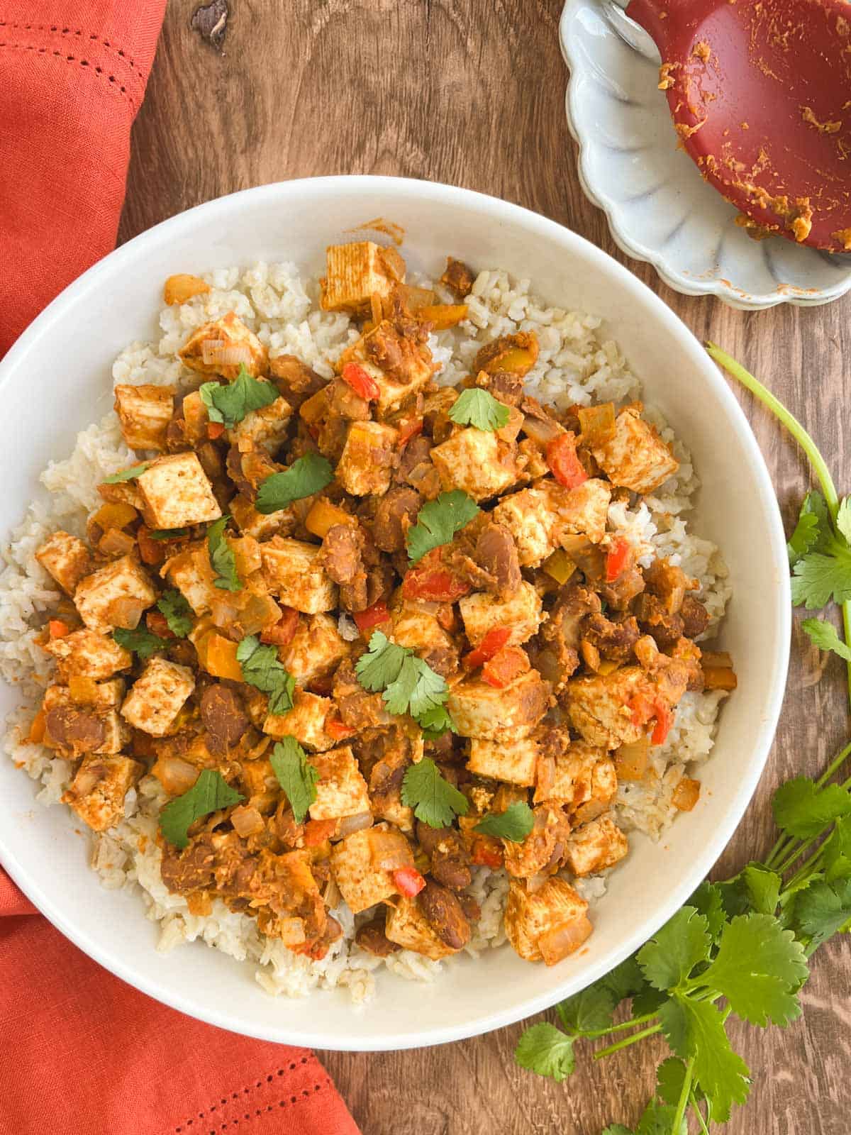 bowl of Tex-Mex skillet supper next to fresh cilantro and a red serving spoon