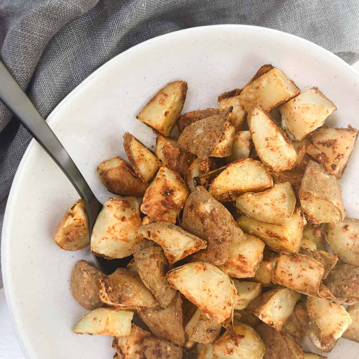 oil-free roasted potatoes in a bowl next to a gray linen napkin