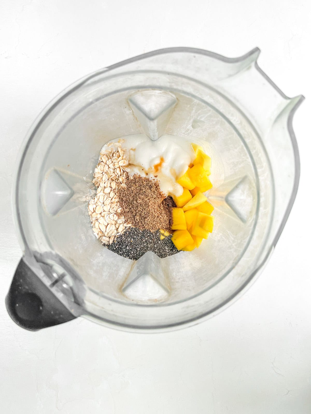 A blender filled with ingredients for mango overnight oats