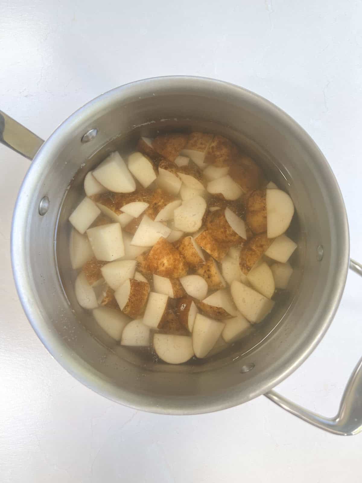 A pot filled with diced potatoes and water