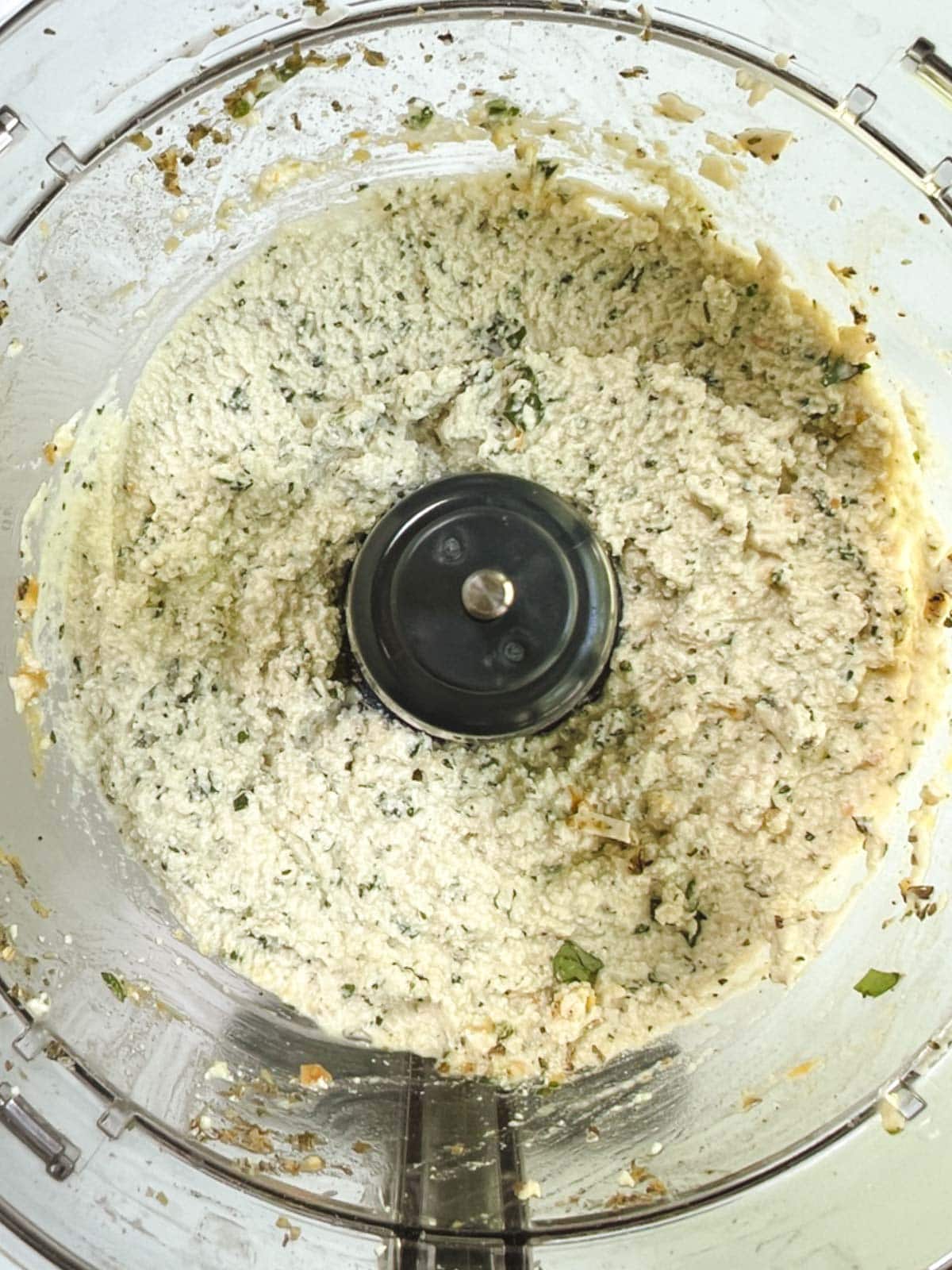 A food processor filled with a whipped basil ricotta