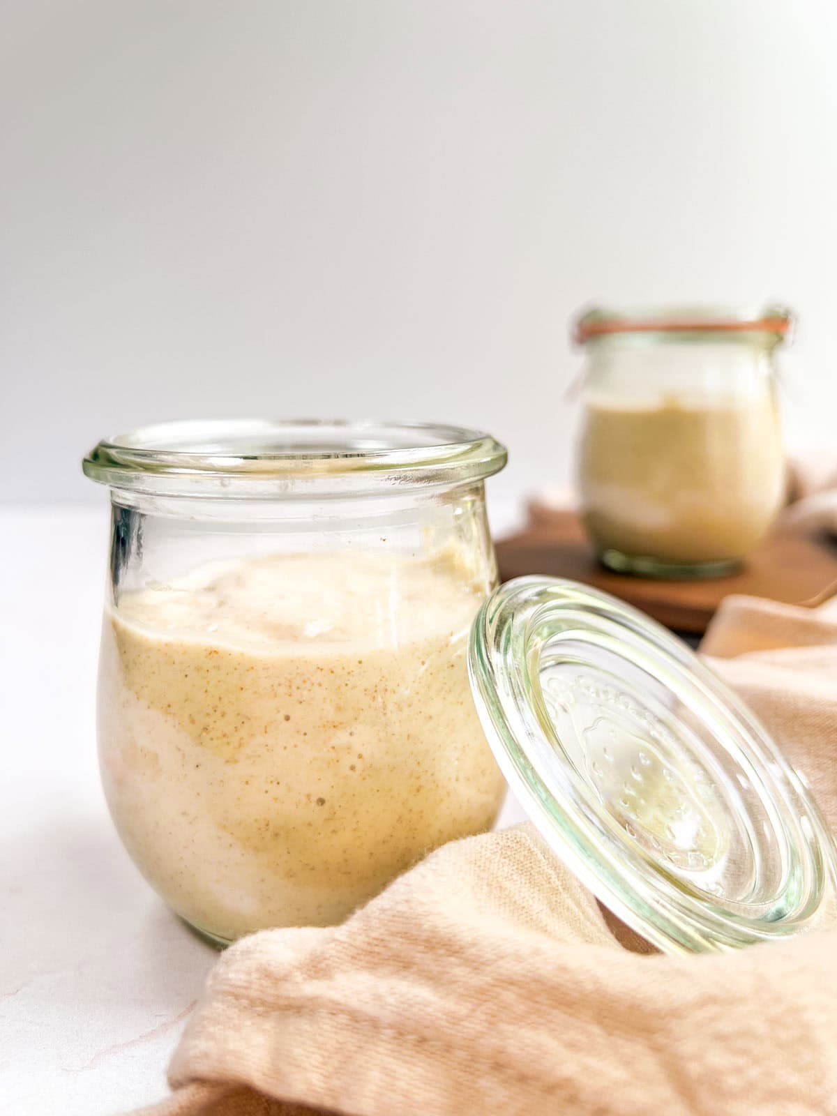 Two jars of mango overnight oats sitting on a wooden board