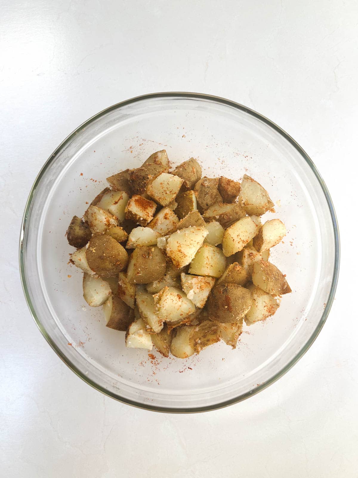 A bowl of potatoes with spices in it