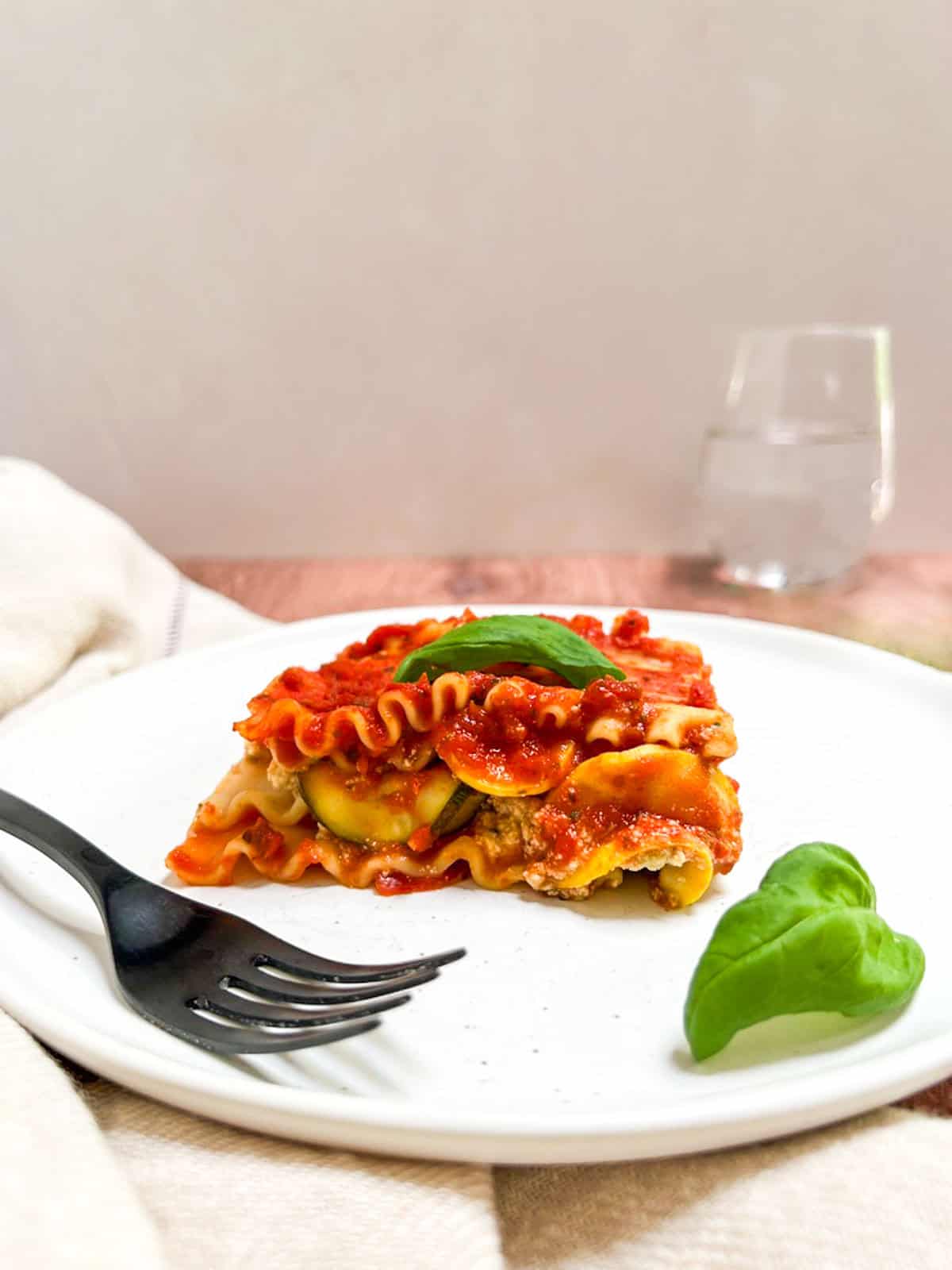 A slice of vegan zucchini lasagna on a plate with a fork