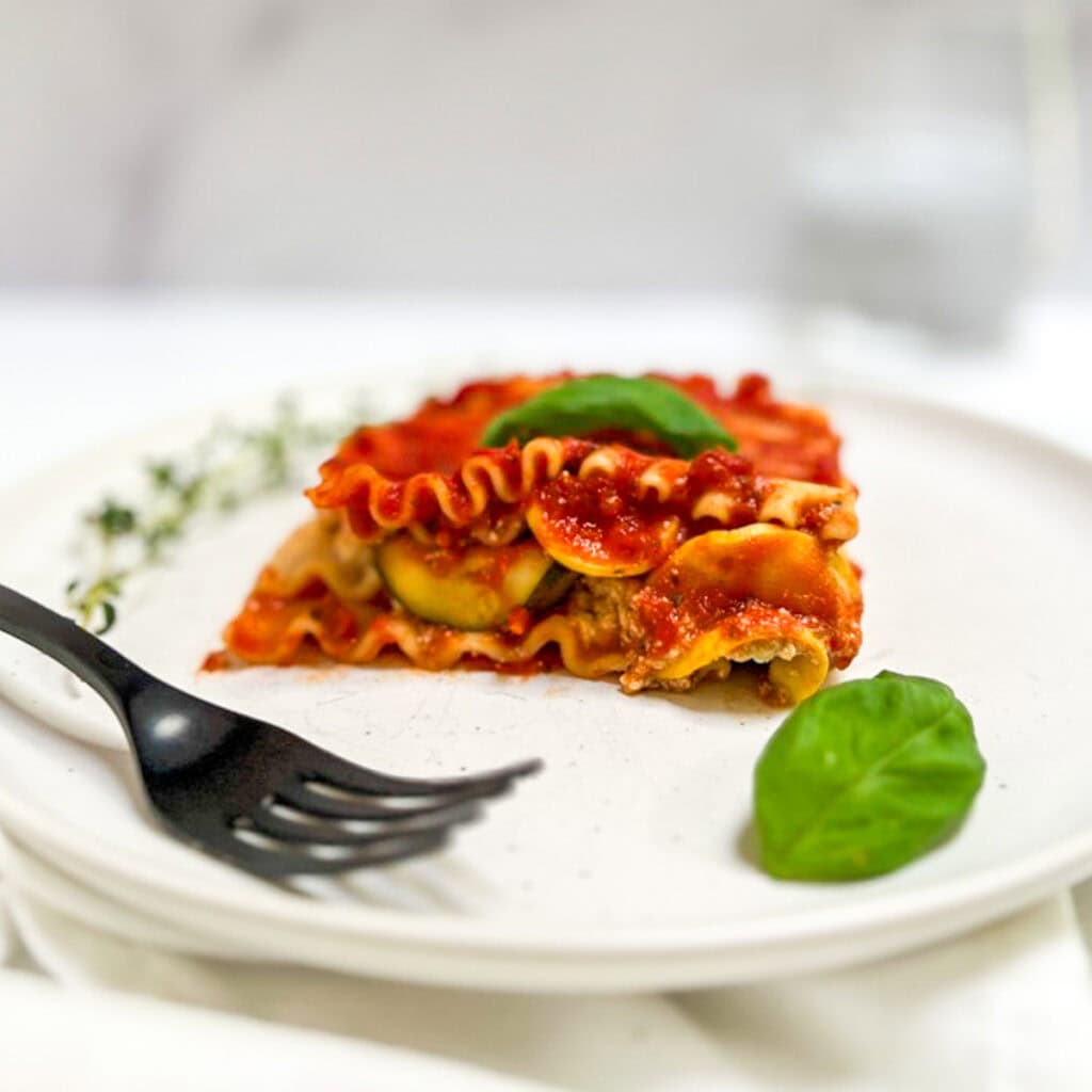 A slice of vegan zucchini lasagna on a plate with a fork