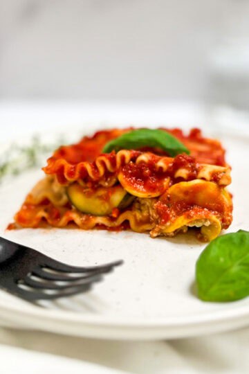 A slice of vegan zucchini lasagna on a plate with a fork