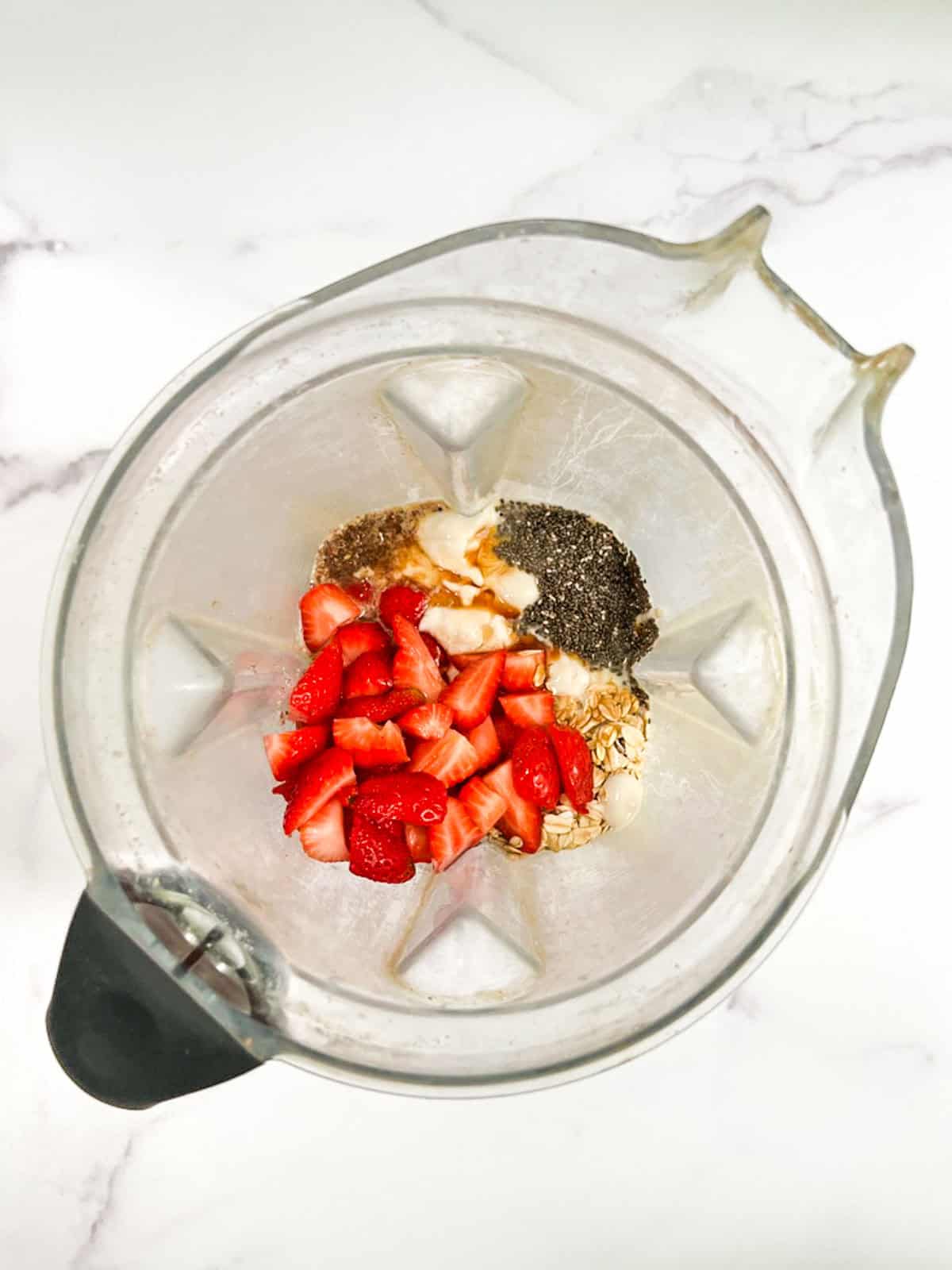 Strawberries, chia seeds, and other ingredients in a blender.