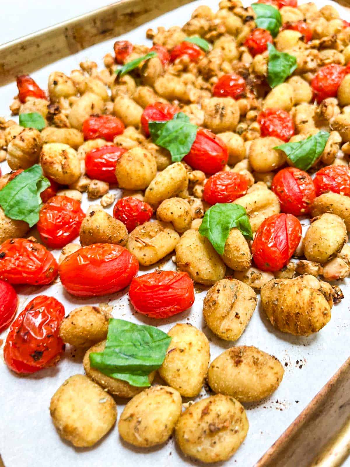 Roasted gnocchi and tomatoes on a baking sheet.