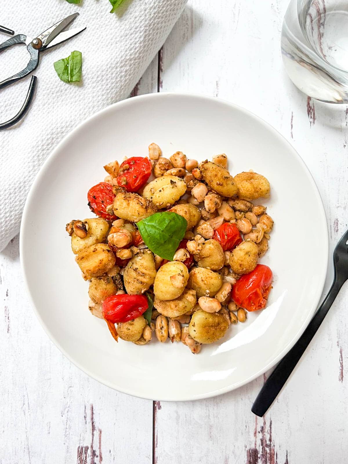 A plate of gnocchi with tomatoes and basil.