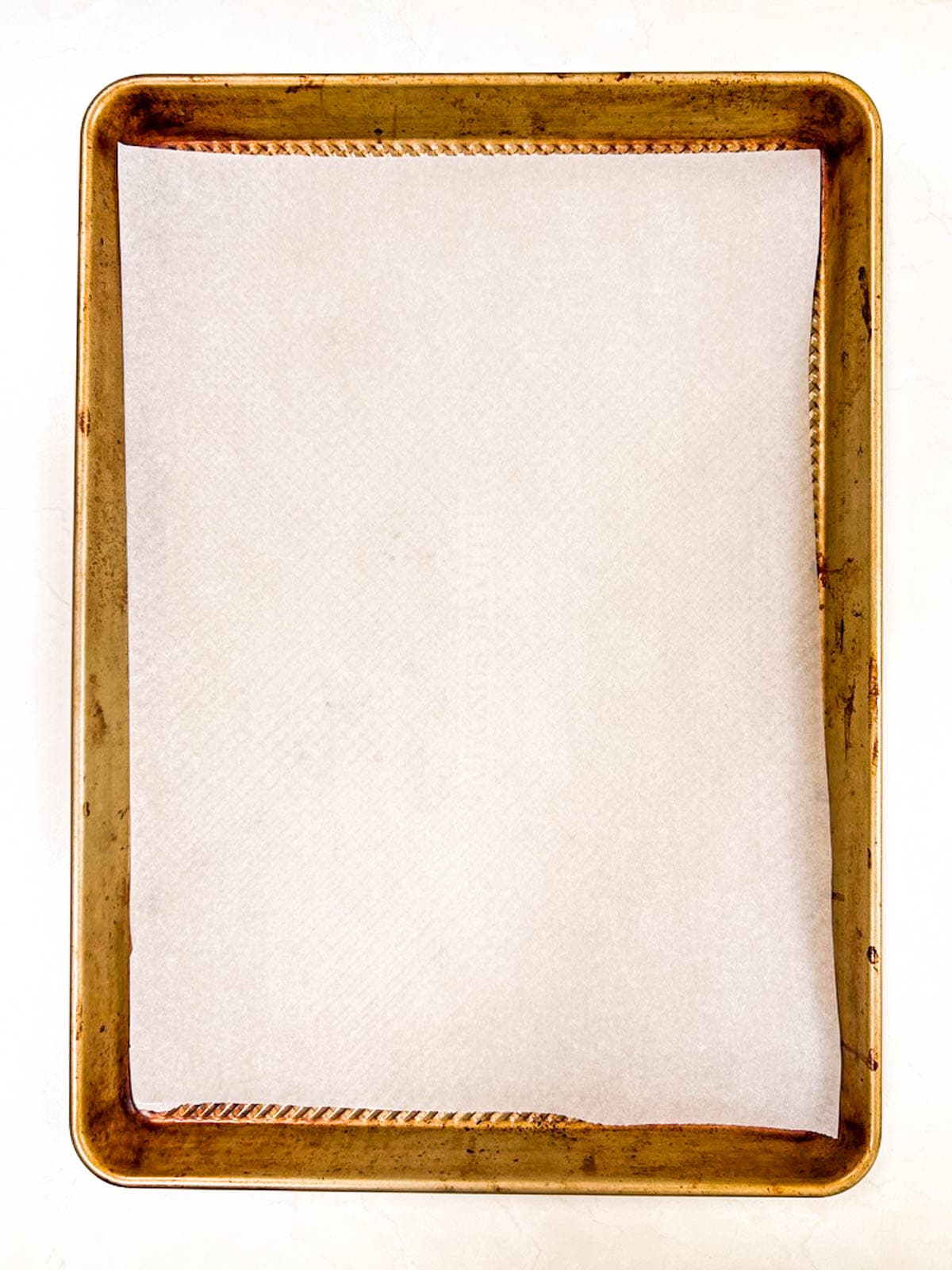 A square of white parchment paper in a metal sheet pan.