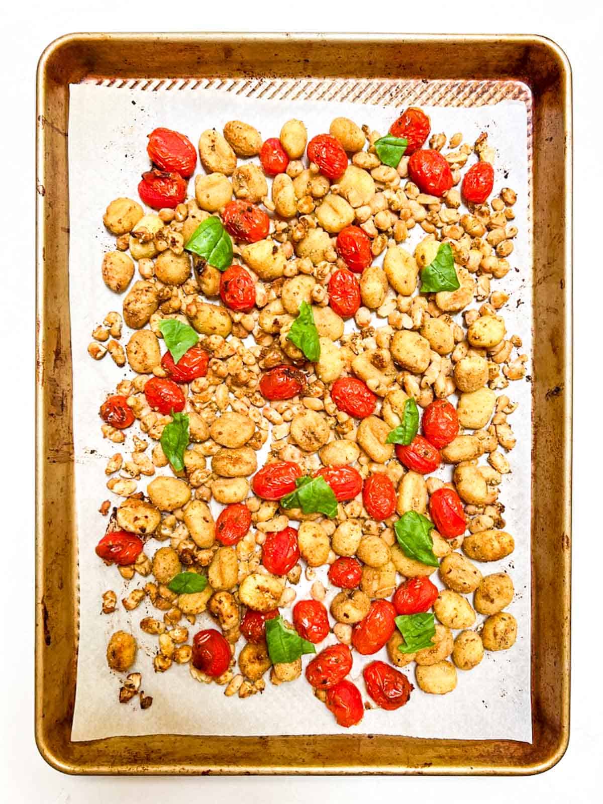 A sheet pan filled with roasted tomatoes and gnocchi.