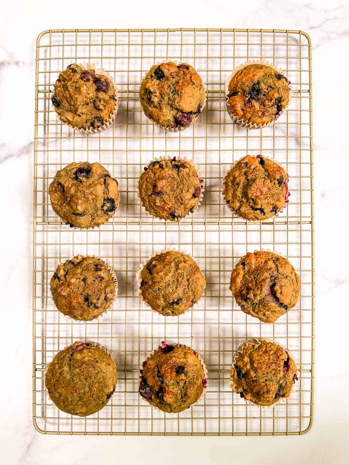 A cooling rack with blueberry muffins on it.