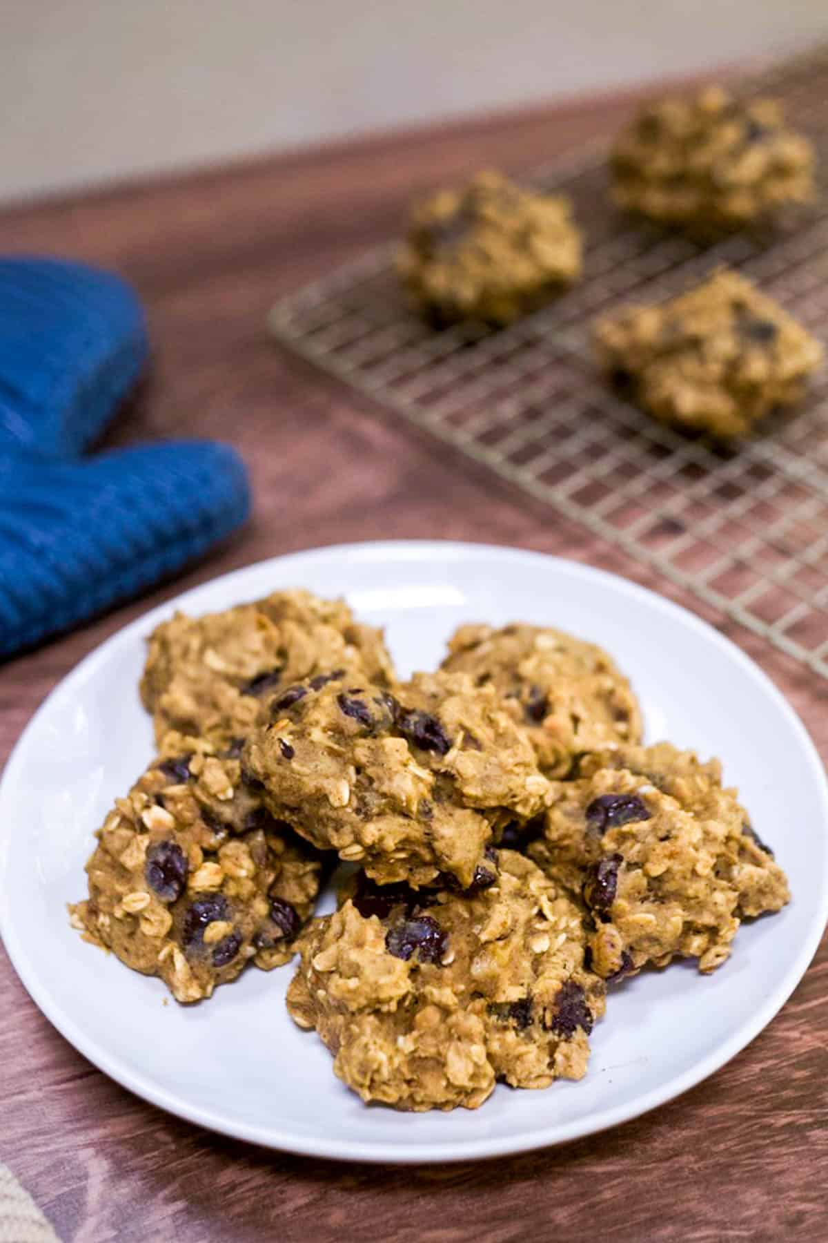 A plate of cookies on a table with a blue oven mitt.